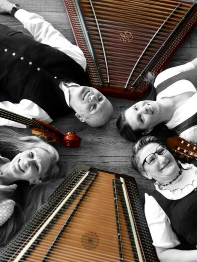 A group of musicians is lying on the ground and surrounded by traditional musical instruments. The scene is partially black and white, highlighting the instruments. | © Salterina