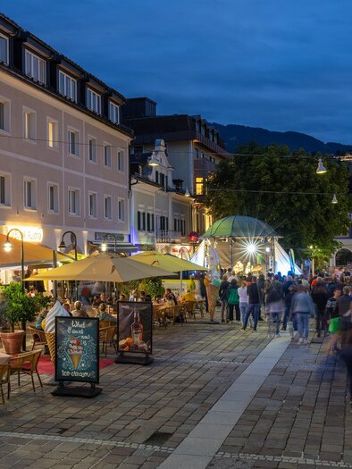 Ein belebter Platz mit gemütlichen Cafés und Restaurants bei Nacht. Viele Menschen genießen die Atmosphäre unter den Lichtern. | © Harald Steiner