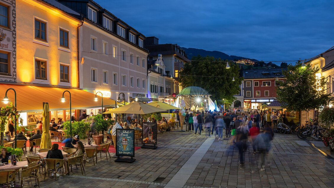 Ein lebhaftes Stadtviertel am Abend mit beleuchteten Restaurants und einer belebten Straße. Menschen genießen die Atmosphäre und die gemütliche Umgebung. | © Harald Steiner