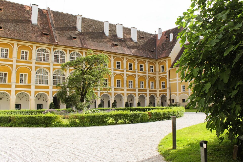 Ein historisches Gebäude mit gelber Fassade und großen Fenstern. Umgeben von gepflegten Grünflächen und Bäumen. | © TV Südsteiermark - Irene Löschnig