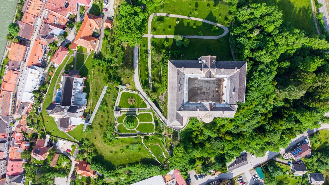 Eine Luftaufnahme einer Stadt mit einem großen Park und historischen Gebäuden. Das grüne Areal ist von Straßen und Häusern umgeben.