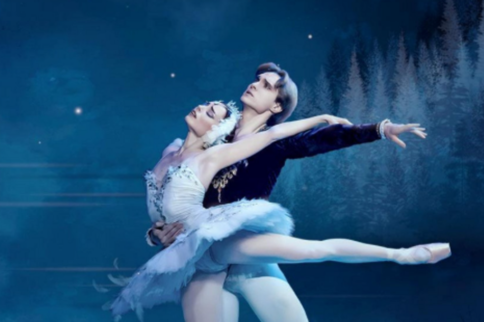 Ein Paar Balletttänzer in eleganten weißen Kostümen tanzt unter einem großen Mond. Im Hintergrund sind sanfte Bäume und fliegende Vögel zu sehen. | © KK