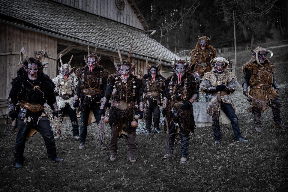 Eine Gruppe von verkleideten Personen mit Hörnern und auffälligen Kostümen steht vor einem Holzhaus. Die Umgebung wirkt mystisch und geheimnisvoll. | © Marktgemeinde Kraubath