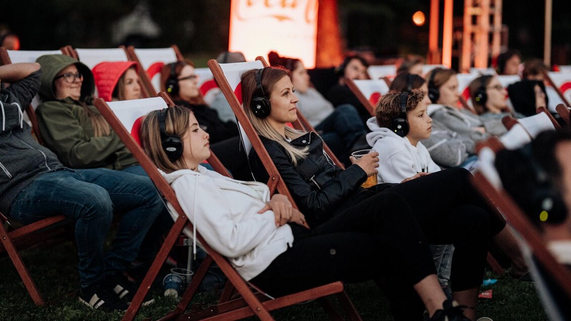 Eine Gruppe von Menschen sitzt in Liegestühlen und hört leise Filme mit Kopfhörern. Der Abend ist entspannt und die Atmosphäre ist gemütlich. | © Silent Cinema