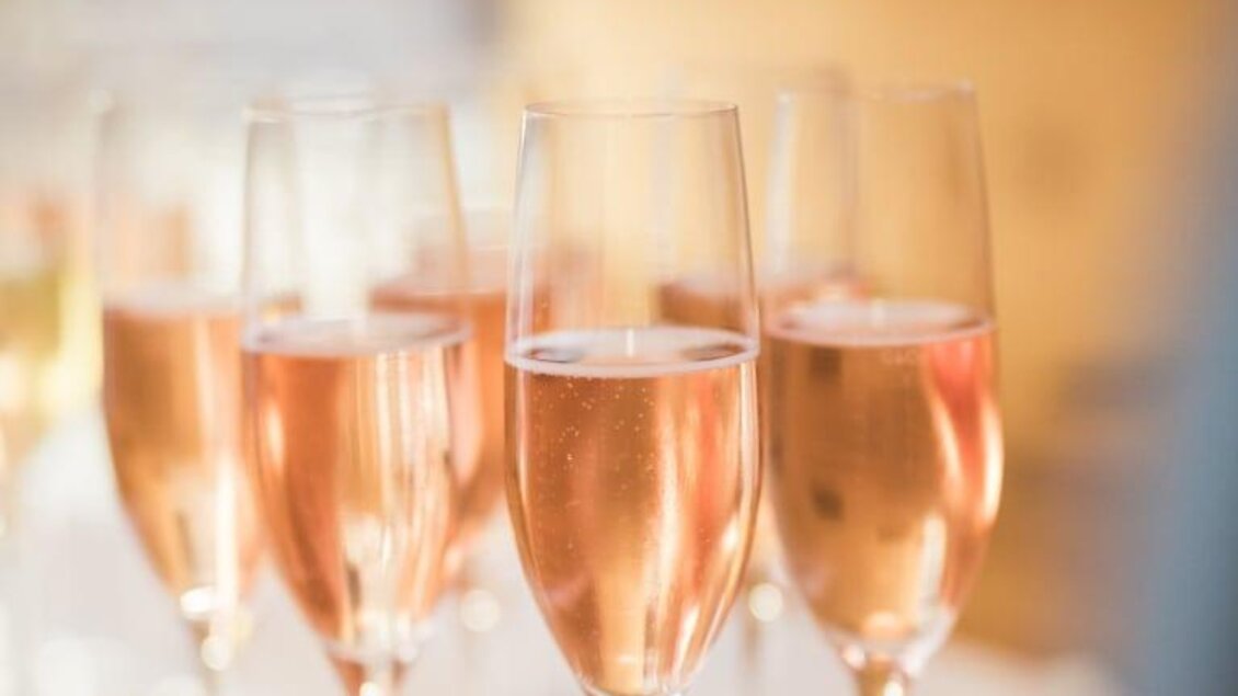 Eine Reihe von Gläsern mit rosé Champagner steht auf einem Tisch. Die Blasen im Getränk funkeln im Licht. | © Garten Hotel Ochensberger