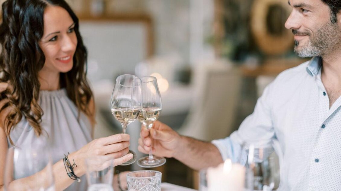 Ein romantisches Dinner mit einem Paar, das Gläser mit Sekt anstößt. Der Tisch ist elegant gedeckt und die Stimmung ist festlich. | © Garten Hotel Ochensberger