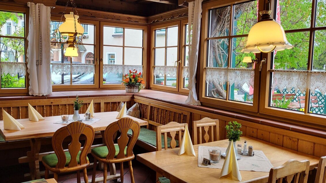 Ein gemütliches Restaurant mit Holzmöbeln und großen Fenstern. Der Raum ist freundlich und hell, mit Blumen und dekorativen Lampen. | © Petra Kirchschlager