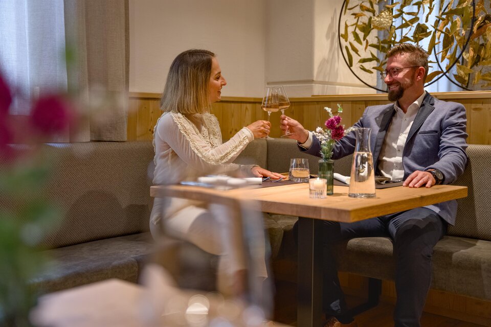 Ein elegantes Restaurant mit einem Tisch, an dem ein Paar anstößt. Die Atmosphäre ist gemütlich und einladend. | © MotionManager_Chris Zarfl