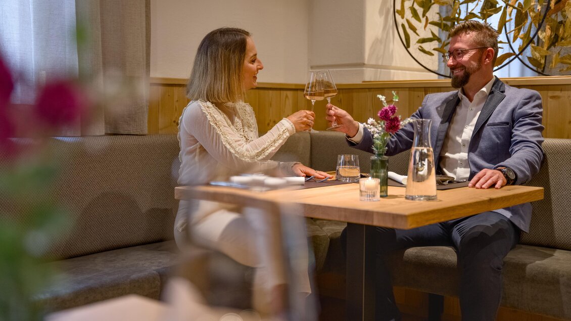 Ein elegantes Restaurant mit einem Tisch, an dem ein Paar anstößt. Die Atmosphäre ist gemütlich und einladend. | © MotionManager_Chris Zarfl