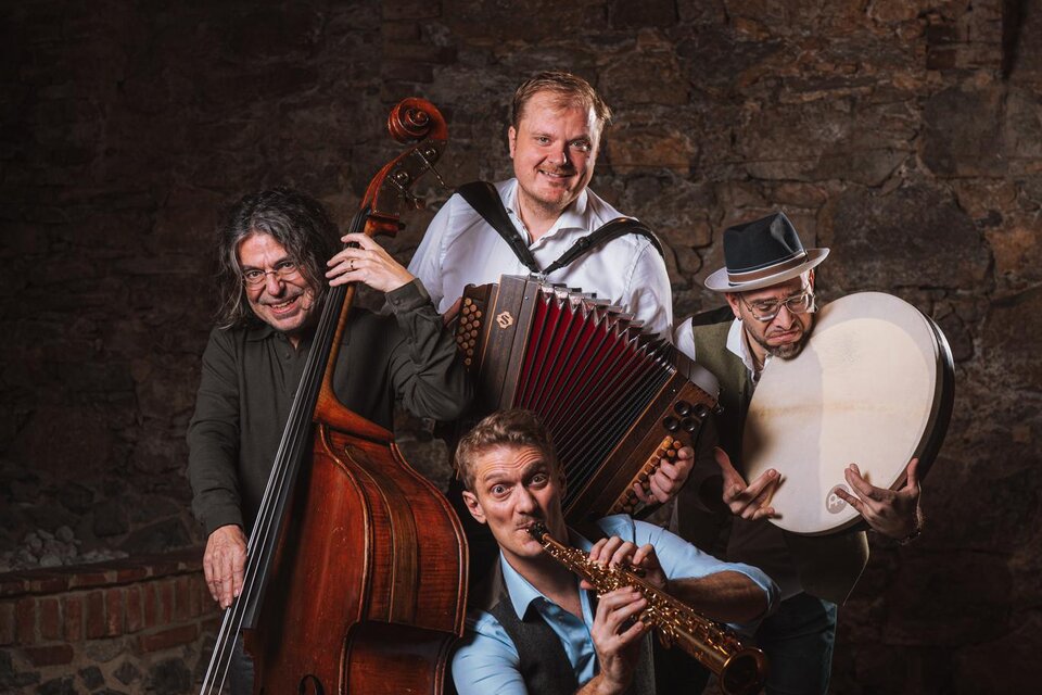 Eine Gruppe von vier Musikern posiert in einem alten Raum. Sie spielen verschiedene Instrumente wie Kontrabass, Akkordeon und Flöte. | © reithofer_media
