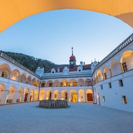 A historical courtyard with impressive architecture. The soft colors of the sky give the scene a tranquil atmosphere. | © Gartenschloss Herberstein