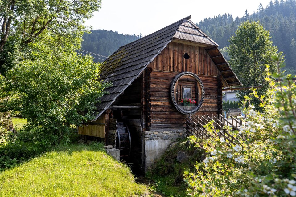 Eine alte Mühle aus Holz mit einem wasserrädern. Sie steht umgeben von grünen Wiesen und Bäumen in einer idyllischen Landschaft. | © Tv Murau