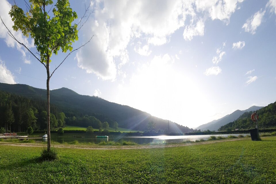 Eine ruhige Landschaft mit einem See und sanften Hügeln im Hintergrund. Der Himmel ist klar und die Sonne scheint hell. | © Gemeinde Wald am Schoberpaß