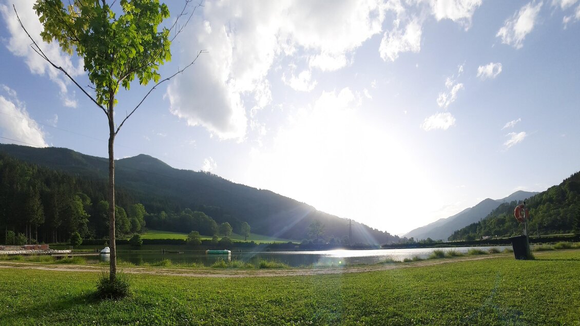Eine ruhige Landschaft mit einem See und sanften Hügeln im Hintergrund. Der Himmel ist klar und die Sonne scheint hell. | © Gemeinde Wald am Schoberpaß