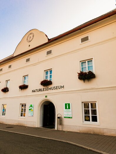 A historic building with the inscription "Nature Museum". The facade is painted light and has windows with flower boxes. | © Tv Murau