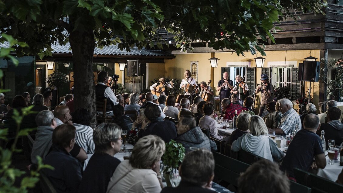 Eine lebhafte Aufführung im Freien mit einer großen Menschenmenge. Musikanten spielen, während die Gäste entspannt sitzen und zuschauen. | © Ulrike Rauch