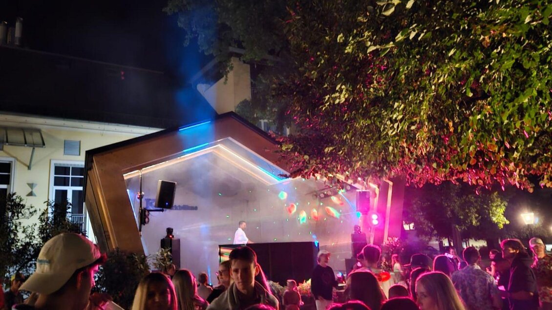 Das Sommernacht Clubbing im Kurpark Bad Aussee. DJ BernArdo steht im Parvillon und sorgt mit roten  Lichteffekten und Nebel für Open-Air-Feeling. Zahlreiche Besucher genießen die Musik und feiern gemeinsam unter freiem Himmel. | © Stadtmarketing Bad Aussee, stadtmarketing-badaussee.at