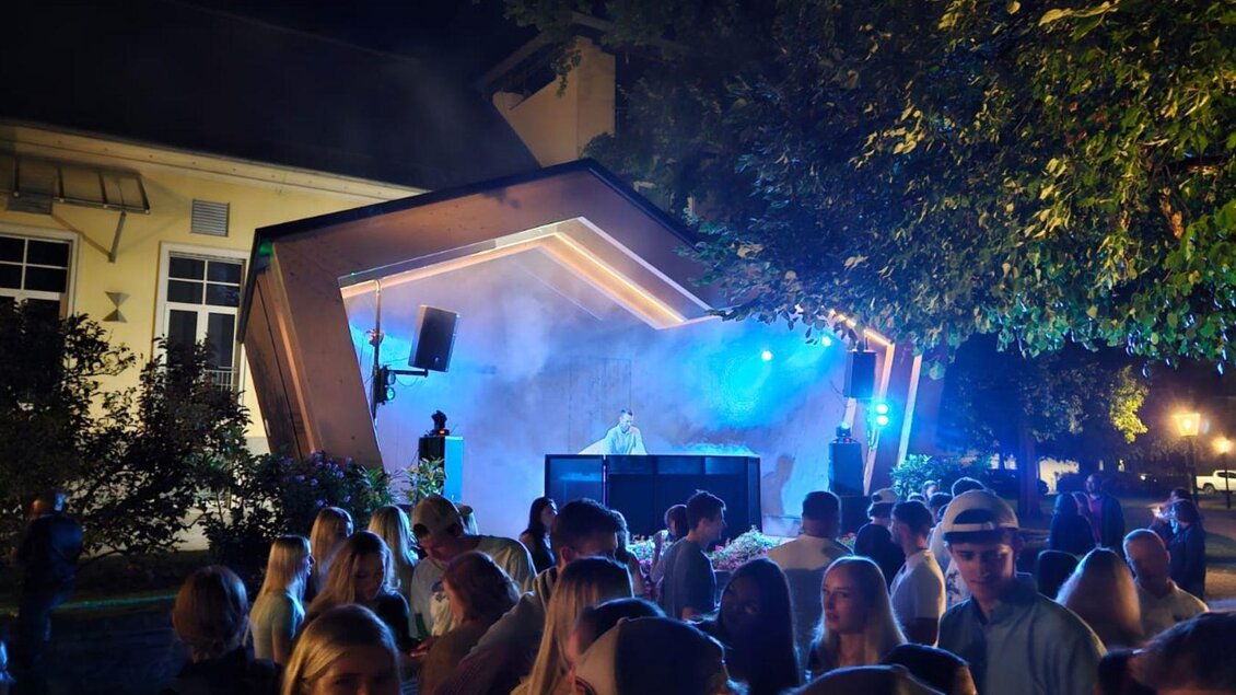 Das Sommernacht Clubbing im Kurpark Bad Aussee. DJ BernArdo steht im Parvillon und sorgt mit blauen Lichteffekten und Nebel für Open-Air-Feeling. Zahlreiche Besucher genießen die Musik und feiern gemeinsam unter freiem Himmel. | © Stadtmarketing Bad Aussee, stadtmarketing-badaussee.at/