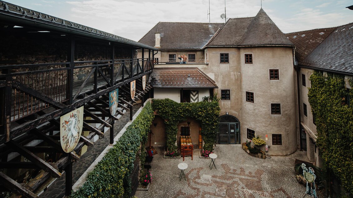 Ein historischer Innenhof mit alten Gebäuden und grünem Efeu. Der Platz ist mit Steinen gestaltet und es gibt einige Sitzgelegenheiten. | © nicoleseiser.at