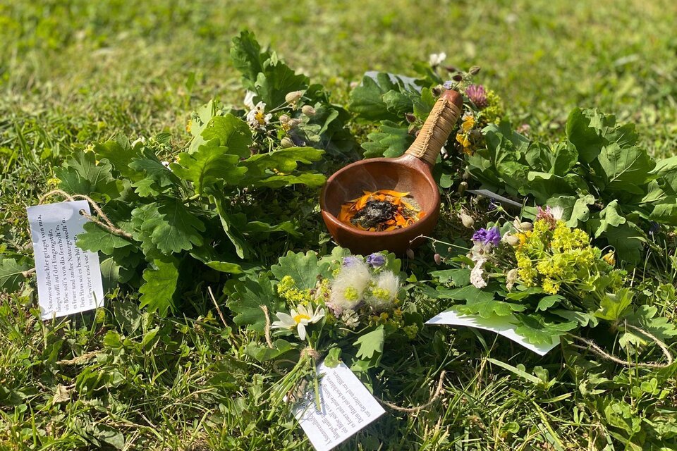 Eine Ansammlung von verschiedenen Kräutern und Blumen liegt auf dem Gras. In der Mitte befindet sich eine kleine Schale mit einer Mischung. | © Andrea Percht