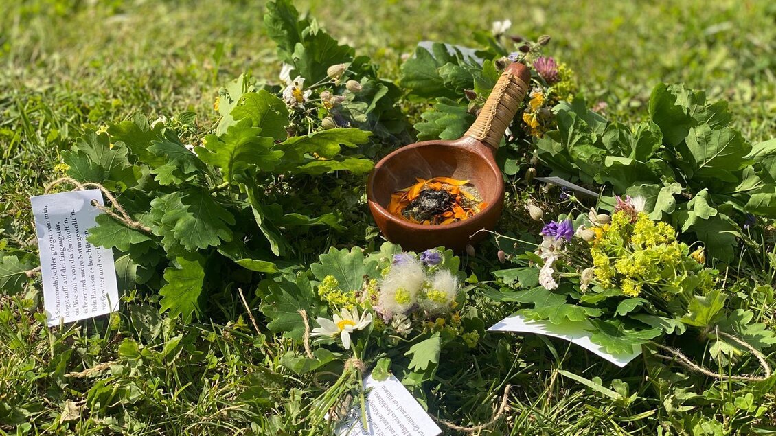 Eine Ansammlung von verschiedenen Kräutern und Blumen liegt auf dem Gras. In der Mitte befindet sich eine kleine Schale mit einer Mischung. | © Andrea Percht