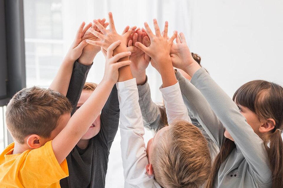 Eine Gruppe von Kindern, die ihre Hände in die Höhe heben. Sie scheinen erfreut und engagiert zu sein. | © Bild: freepik