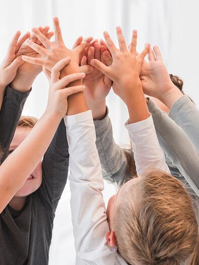 Eine Gruppe von Kindern, die ihre Hände in die Höhe heben. Sie scheinen erfreut und engagiert zu sein. | © Bild: freepik