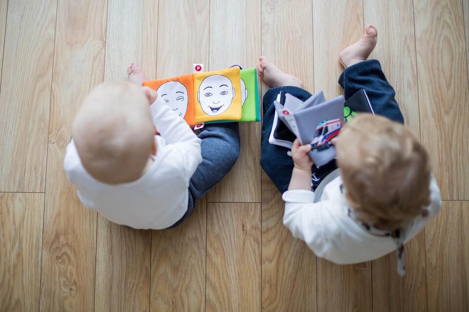 Zwei kleine Kinder sitzen auf dem Boden und schauen sich bunte Bilderbücher an. Sie halten jeweils ein Buch in den Händen und scheinen interessiert zu sein. | © Bild: Pixabay