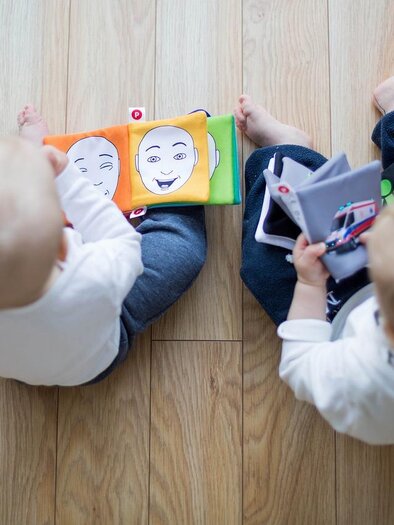 Zwei kleine Kinder sitzen auf dem Boden und schauen sich bunte Bilderbücher an. Sie halten jeweils ein Buch in den Händen und scheinen interessiert zu sein. | © Bild: Pixabay