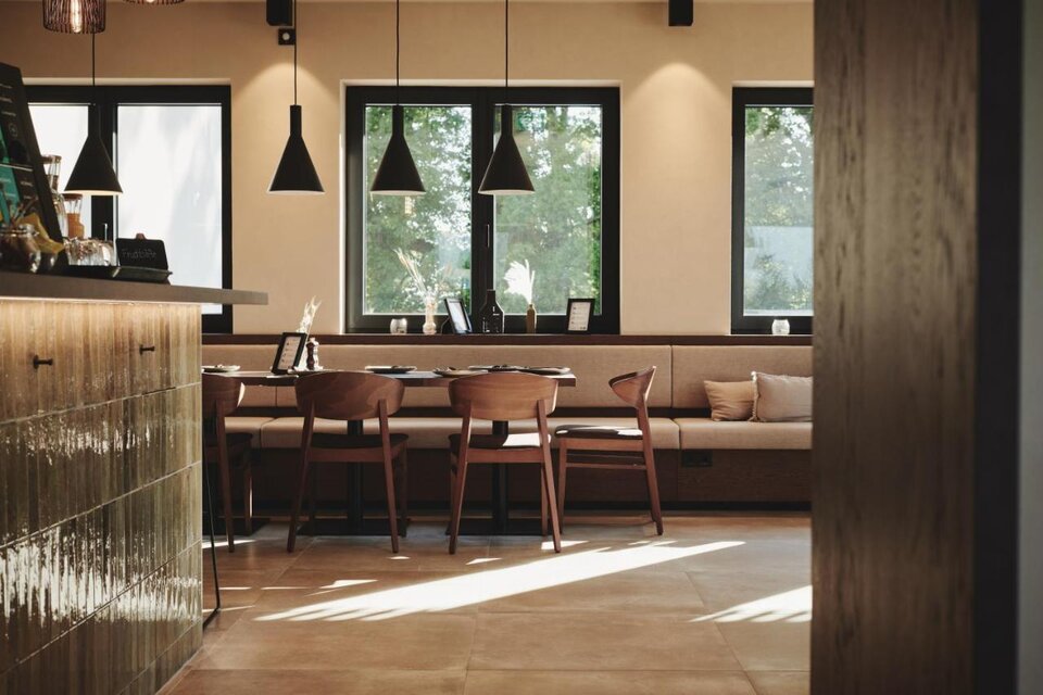 Ein modernes Café mit Holztischen und Stühlen. Große Fenster lassen viel Licht herein und bieten einen Blick ins Grüne. | © Das Zeitwert