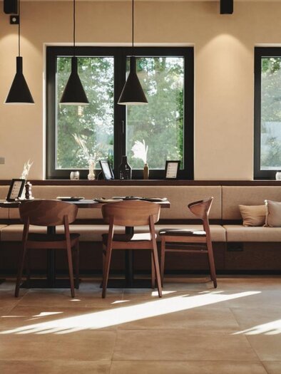 A modern café with wooden tables and chairs. Large windows let in plenty of light and offer a view of the greenery. | © Das Zeitwert
