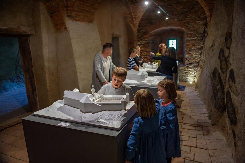 Ein Museum mit Besuchern, die Modelle von historischen Gebäuden betrachten. Einige Kinder stehen an einem Tisch und schauen interessiert auf das Modell. | © Gartenschloss Herberstein
