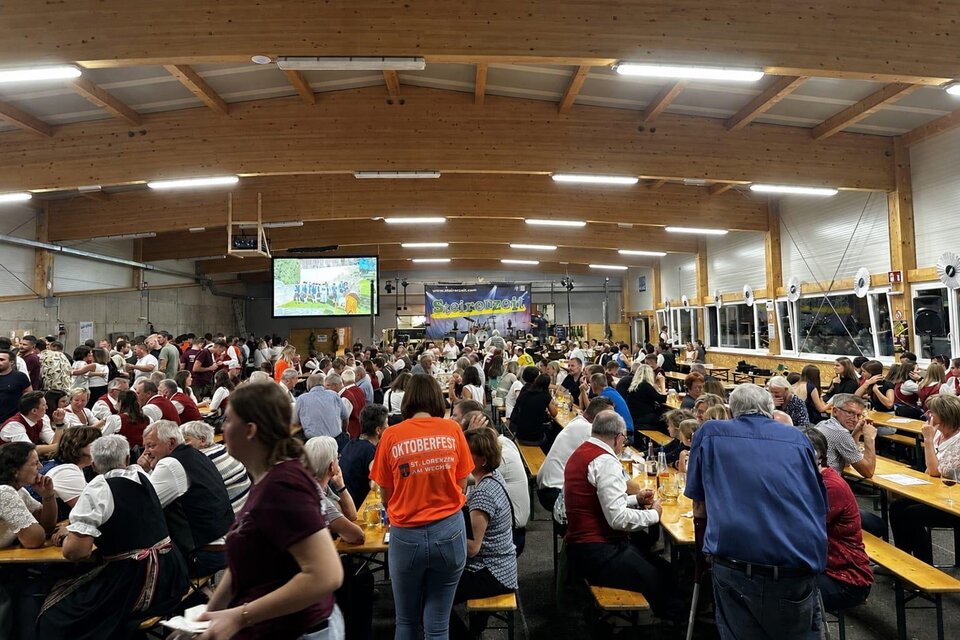 Eine große Menschenmenge feiert in einer Halle mit langen Tischen. Viele tragen traditionsreiche Kleidung und es gibt eine festliche Stimmung. | © USV St. Lorenzen am Wechsel