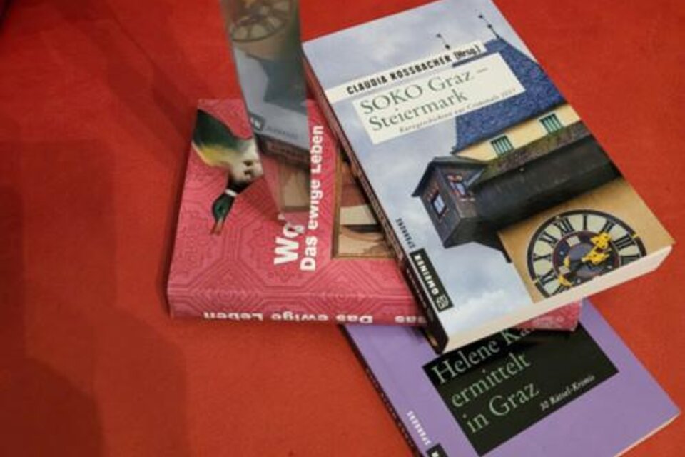 Bücher zu Kriminalfällen in Graz auf rotem Untergrund, Thema Krimi-Führung. | © GrazGuides
