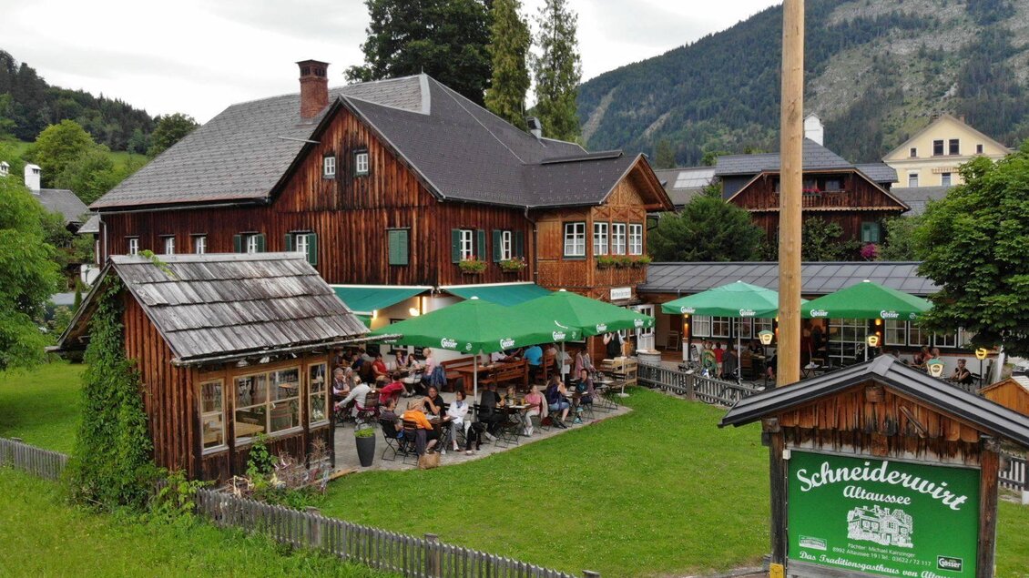 <p>Beim Gasthaus Schneiderwirt genießen die Gäste die angenehme Atmosphäre an der frischen Luft unter grünen Schirmen in Altaussee.</p> | © Gasthaus Schneiderwirt Altaussee