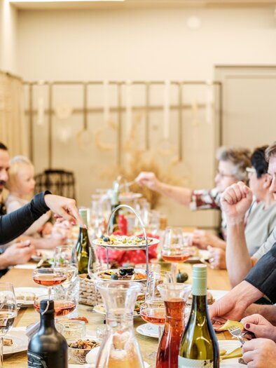 Eine Gruppe von Personen sitzt an einem Tisch und genießt ein gemeinsames Essen. Ein Kellner serviert Gerichte und Getränke. | © Der M-Effekt