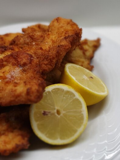 Fried fish fillets on a plate with fresh lemon slices. The golden brown crust makes the dish appetizing. | © Pixabay