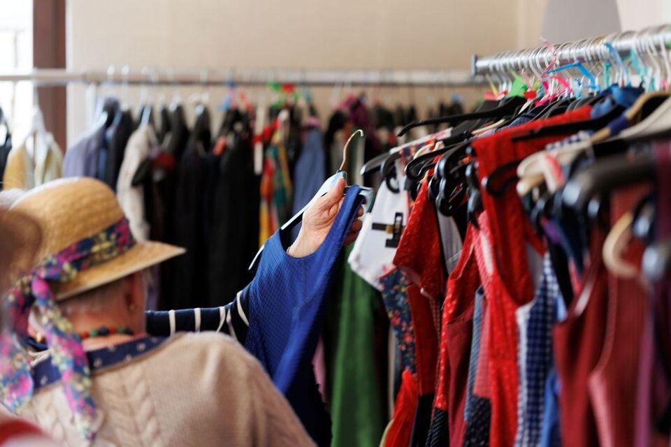 Eine Person schaut sich Kleidung in einem Modegeschäft an. Der Hintergrund zeigt eine Vielzahl von bunten Kleidungsstücken auf Kleiderständern. | © AndersOrt Haus der Frauen