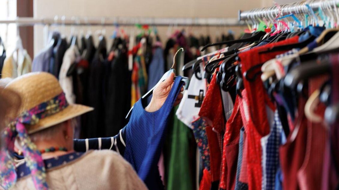 Eine Person schaut sich Kleidung in einem Modegeschäft an. Der Hintergrund zeigt eine Vielzahl von bunten Kleidungsstücken auf Kleiderständern. | © AndersOrt Haus der Frauen