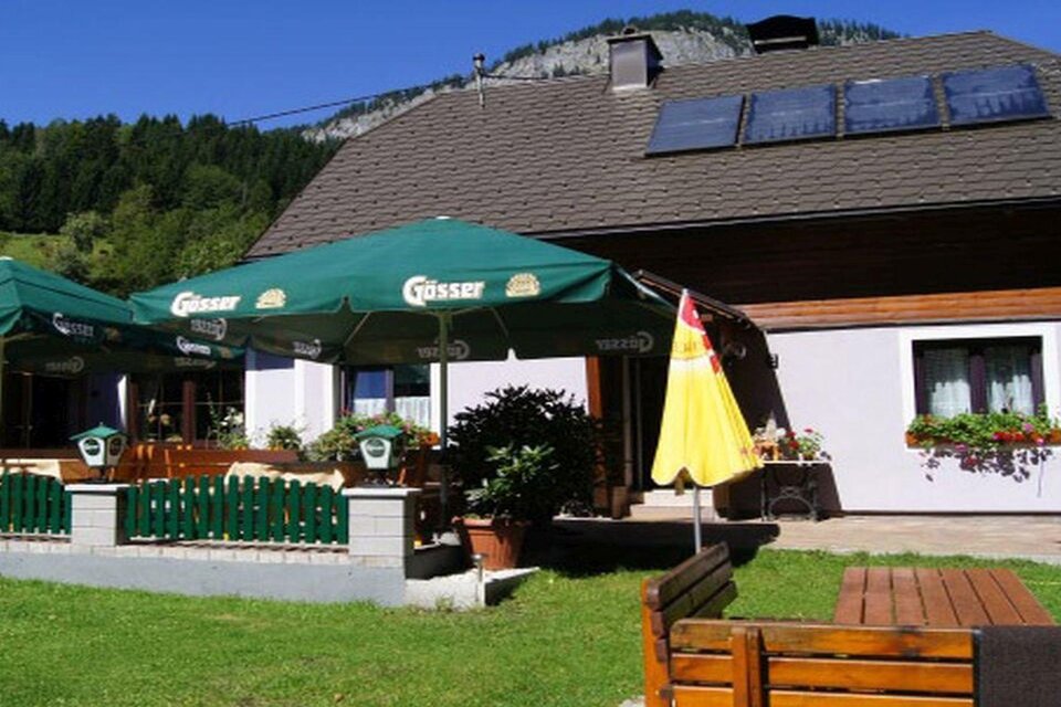 Ein gemütliches Gasthaus mit Sonnenschirmen und einer schönen Terrasse. Im Hintergrund sind Berge und Bäume zu sehen. | © Jägerstüberl Maissl