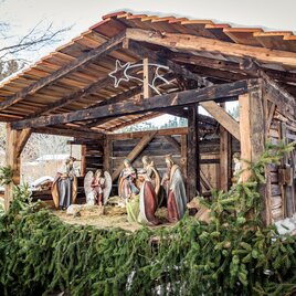 Eine traditionelle Weihnachtskrippe in einem Holzstall, umgeben von Tannenzweigen. Die Figurengruppe zeigt die Geburt Jesu im Winter. | © Naturpark Zirbitzkogel-Grebenzen, Mediadome
