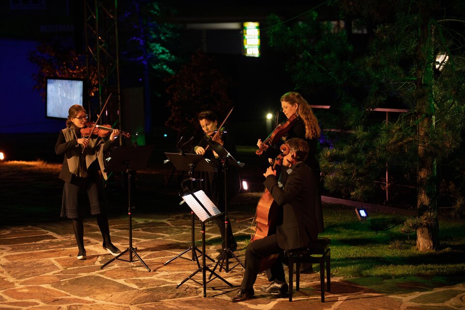 Eine kleine Musikgruppe spielt im Freien. Es sind vier Musiker mit Streichinstrumenten auf einer beleuchteten Fläche zu sehen. | © TVB Südsteiermark