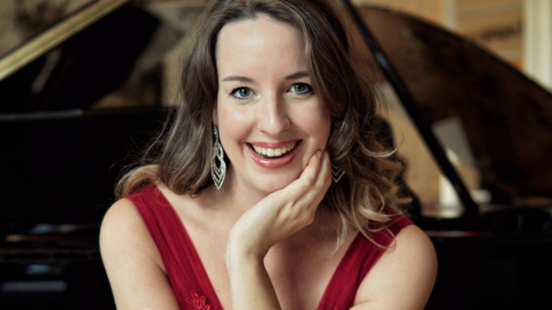 Porträt der Pianistin Irina Vaterl in rotem Kleid vor einem Flügel. | © Fortin