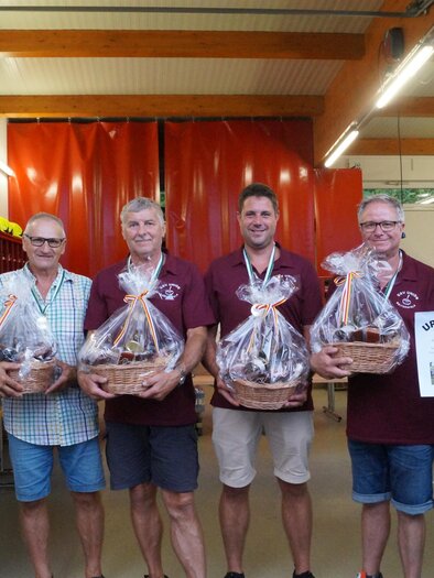 Siegerehrung eines Stockturniers in Gruisla: Gruppe von sechs Männern in Feuerwehrhaus oder Vereinshalle mit Geschenkkörben und Urkunde „1. Platz“, freundliche Atmosphäre, regionale Veranstaltung, Vereinsleben, Teamgeist und Brauchtum. | © FF Gruisla