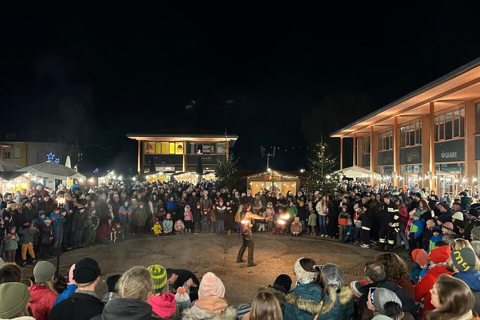 Eine große Menschenmenge versammelt sich bei Nacht, um einer Feuershow zuzusehen. Im Hintergrund sind festlich beleuchtete Stände zu sehen. | © Marktgemeinde Gratwein-Straßengel