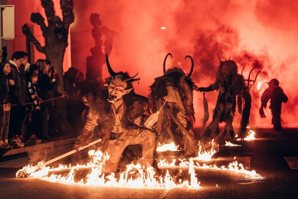 Eine Gruppe von verkleideten Figuren zieht durch eine Straße, umgeben von Feuer und Rauch. Die Atmosphäre ist festlich und zugleich bedrohlich. | © Südsteirische Teufel
