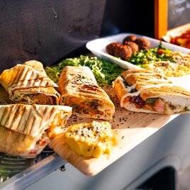 Ein Food Truck mit verschiedenen leckeren Gerichten. Es gibt gefüllte Sandwiches, frische Salate und Snacks auf einem Tisch präsentiert. | © Oststeiermark Tourismus