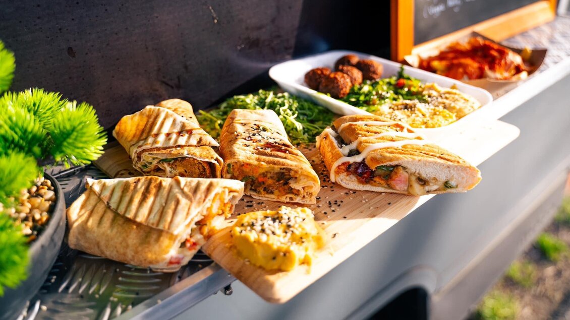 Ein Food Truck mit verschiedenen leckeren Gerichten. Es gibt gefüllte Sandwiches, frische Salate und Snacks auf einem Tisch präsentiert. | © Oststeiermark Tourismus