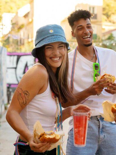 A cheerful group of four friends enjoys food and drinks in a lively environment. They laugh and are clearly having fun together. | © freepik