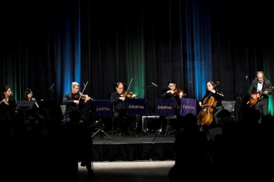 Eine Musikgruppe steht auf der Bühne und spielt verschiedene Instrumente. Im Hintergrund leuchten bunte Lichter. | © Kuturforum Bad Radkersburg